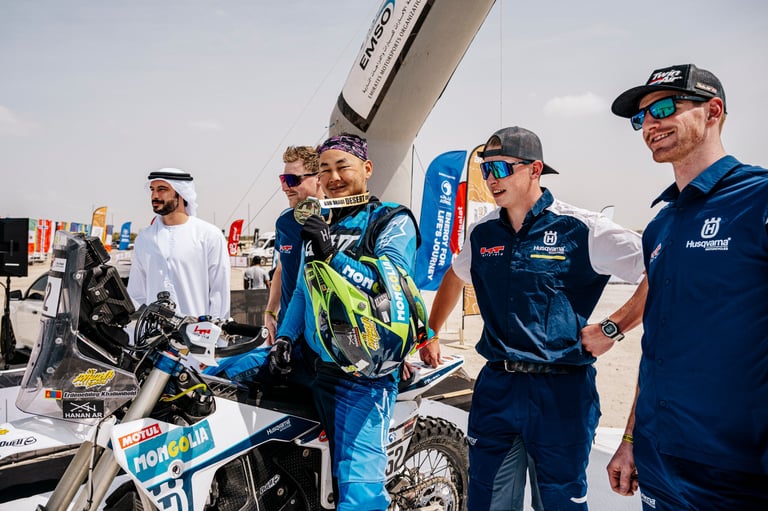 Motocross riders and team members in branded gear standing with dirt bikes at an outdoor racing event