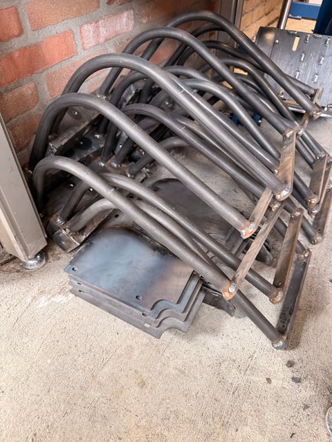 Stack of five metal folding chairs leaning against a brick wall on concrete ground