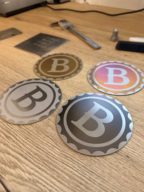 Four circular Bitcoin logo stickers with bottle cap edges arranged on a wooden desk surface