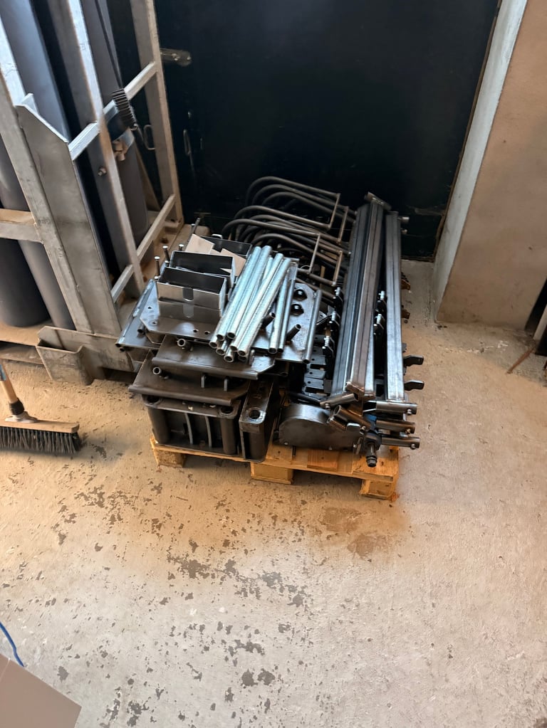 Stack of metal frames and aluminum sheets on wooden pallets in a warehouse or storage area